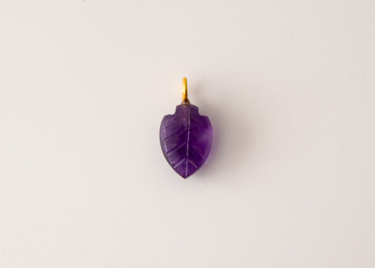 Intricately detailed, this versatile amethyst leaf shaped charm features a delicate leaf design carved from amethyst gemstone, with the pendant ring made of gold plated material, it is  perfect for various jewelry creations like a necklace or earrings, displayed on a neutral background.