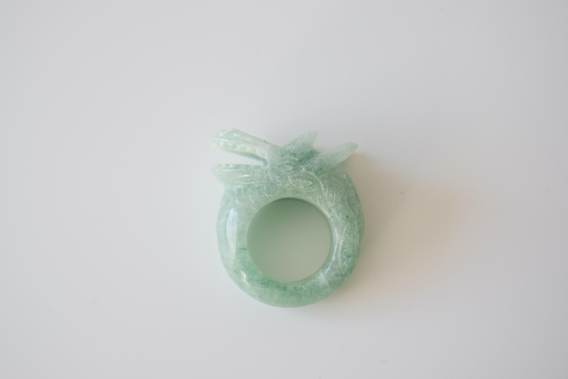 Aventurine stone ring with carved and engraved dragon on a white neutral background