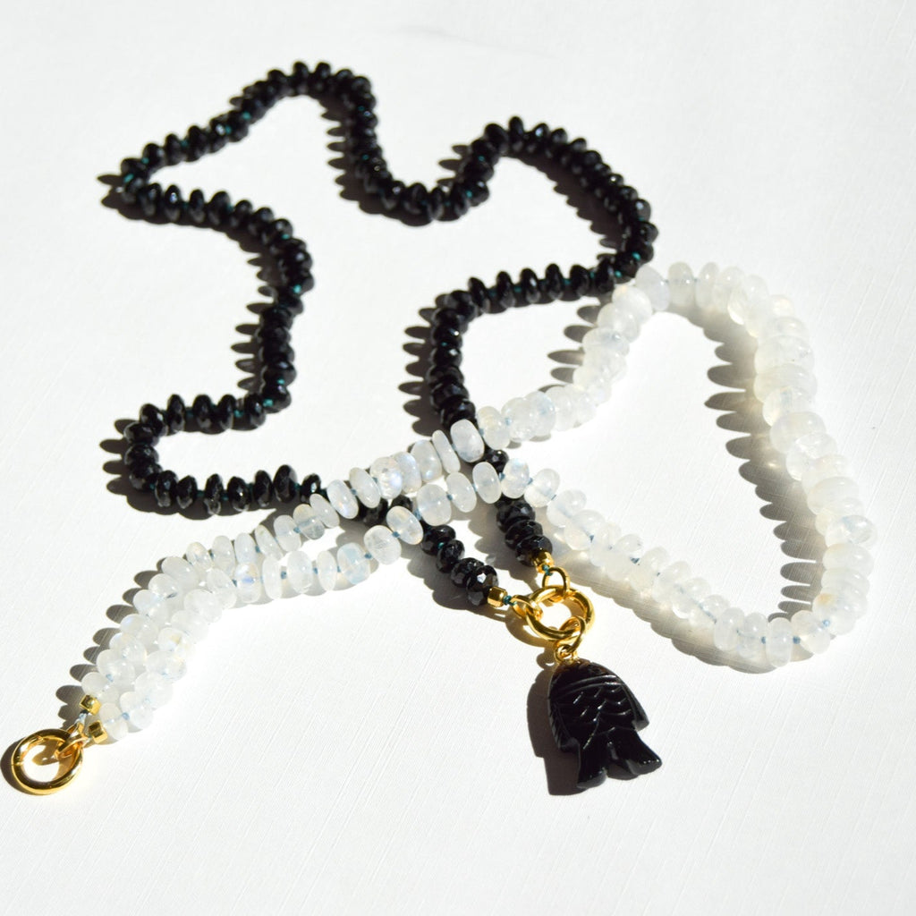 Black, white, and gold beaded necklace with a pendant on a white background