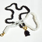 Black, white, and gold beaded necklace with a pendant on a white background