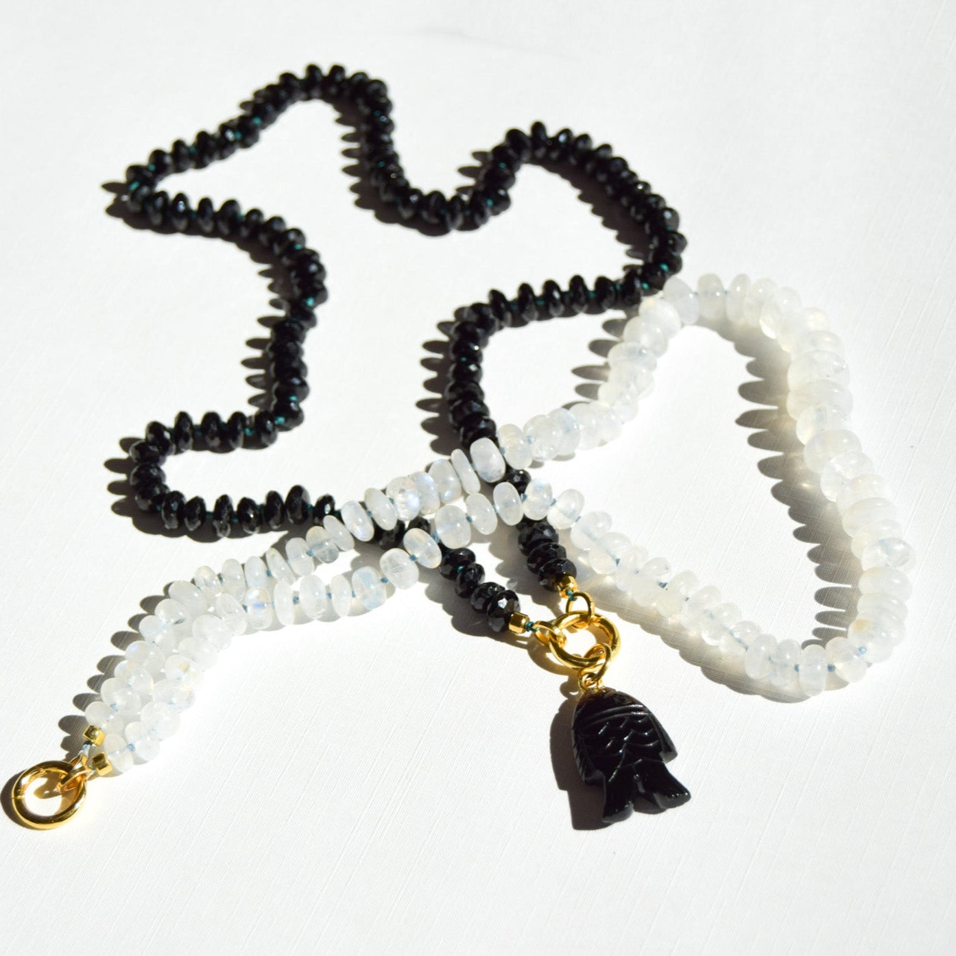 Black, white, and gold beaded necklace with a pendant on a white background