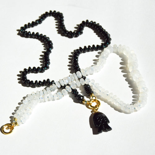 Black, white, and gold beaded necklace with a pendant on a white background