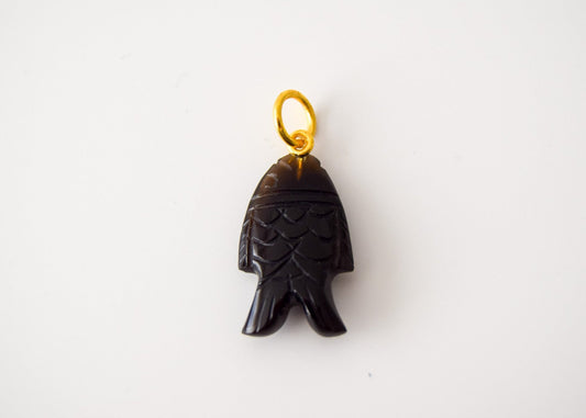 Intricately detailed, this versatile black onyx fish shaped charm features a delicate fish design carved from black onyx gemstone, with the pendant ring made of gold plated material, it is  perfect for various jewelry creations like a necklace or earrings, displayed on a neutral background.