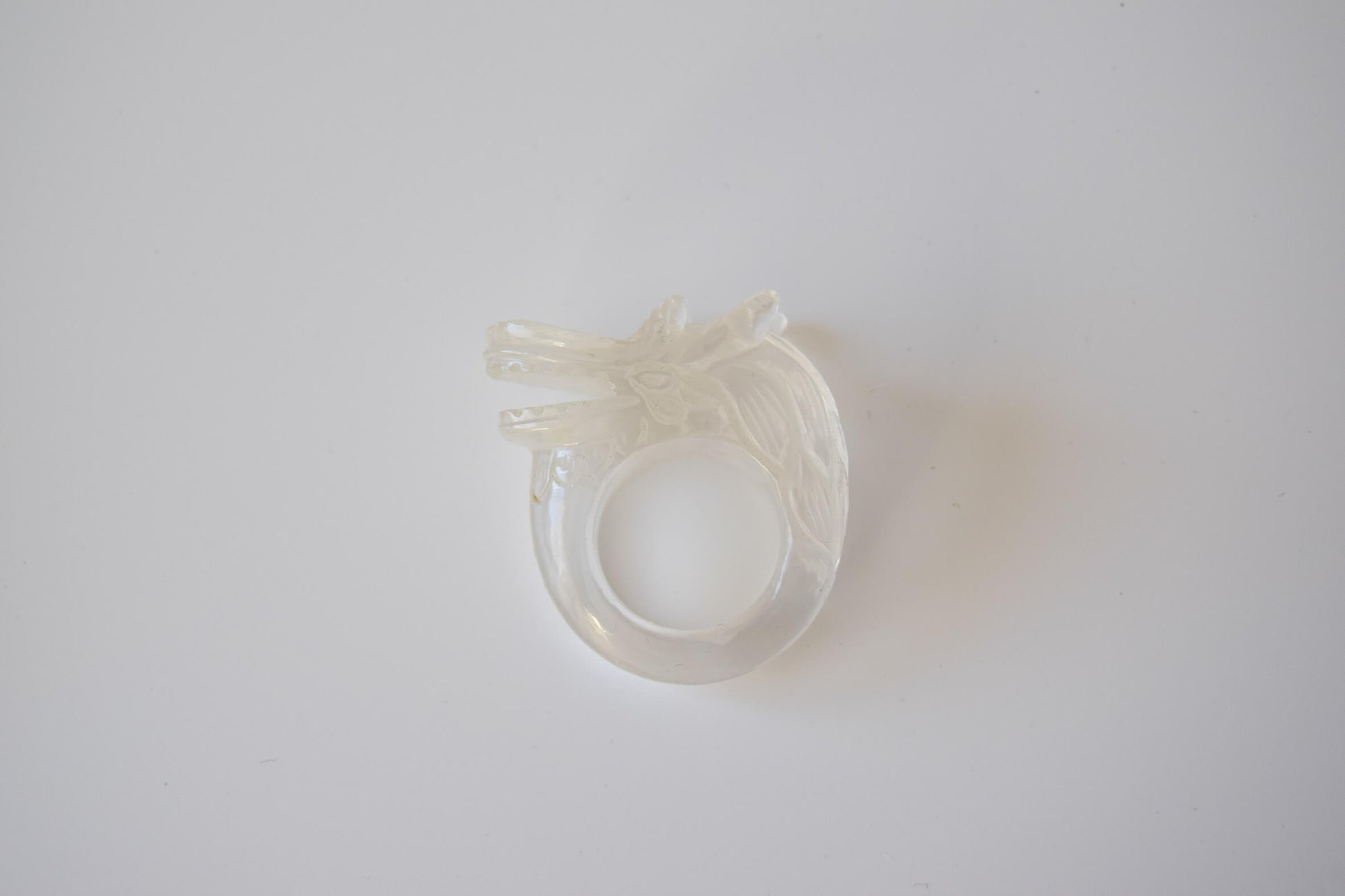 Clear Quartz stone ring with carved and engraved dragon on a white neutral background