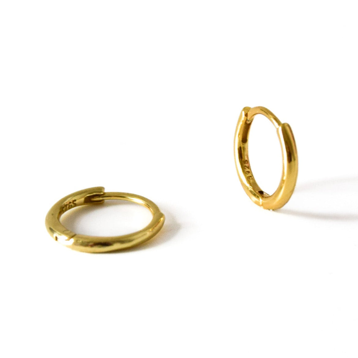 Two gold hoop earrings on a white background