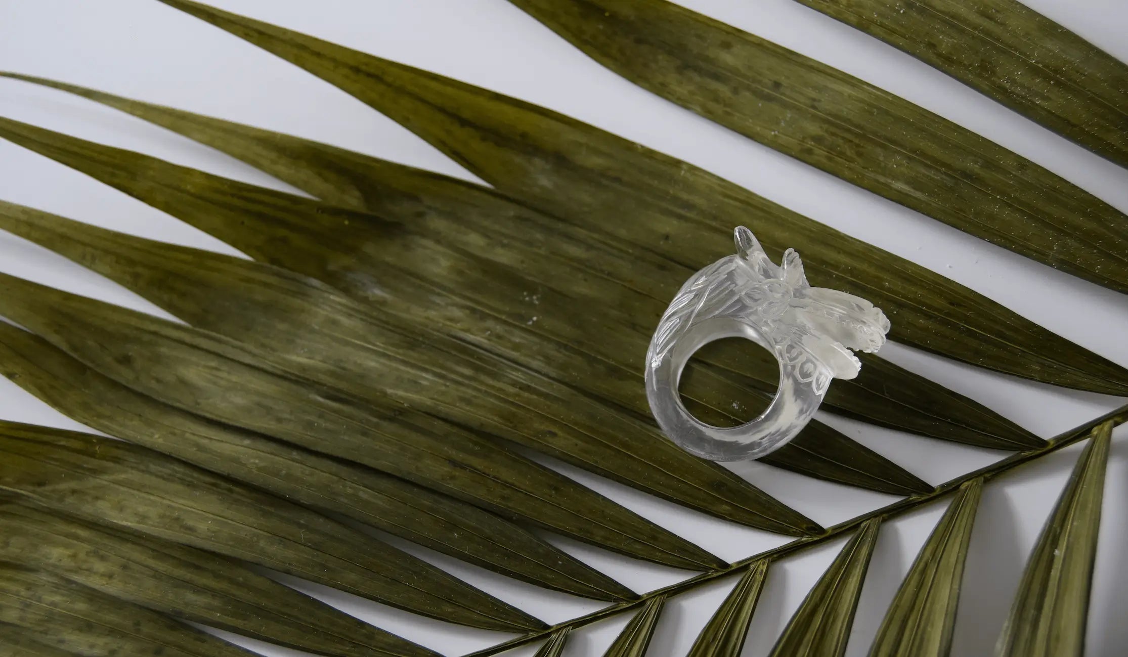 Clear Quartz Dragon Ring displayed on lush tropical leaves. A handcrafted gemstone masterpiece blending elegance and nature's beauty