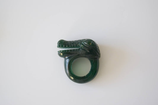 Green Onyx stone ring with carved and engraved crocodile on a neutral background