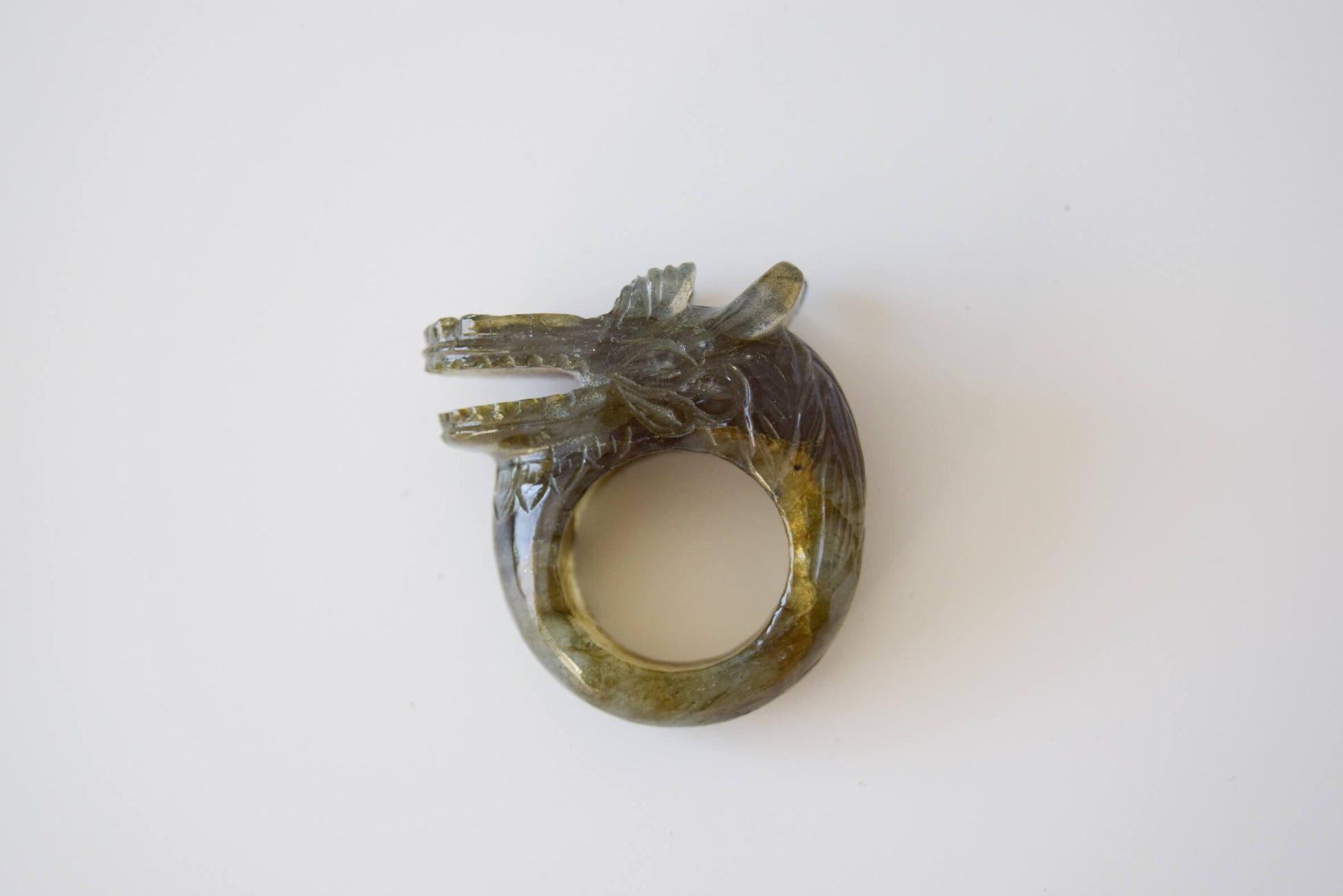 Labradorite stone ring with carved and engraved dragon on a neutral background