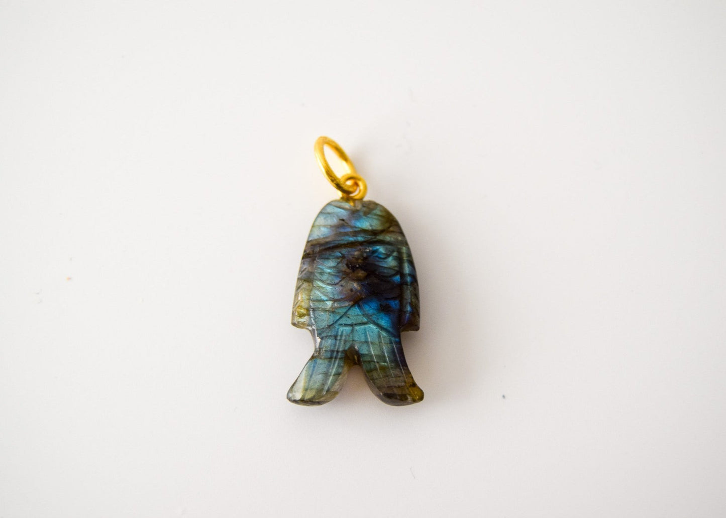 Intricately detailed, this versatile labradorite fish charm features a delicate fish design carved from labradorite gemstone, with the pendant ring made of gold plated material, it is  perfect for various jewelry creations like a necklace or earrings, displayed on a neutral background