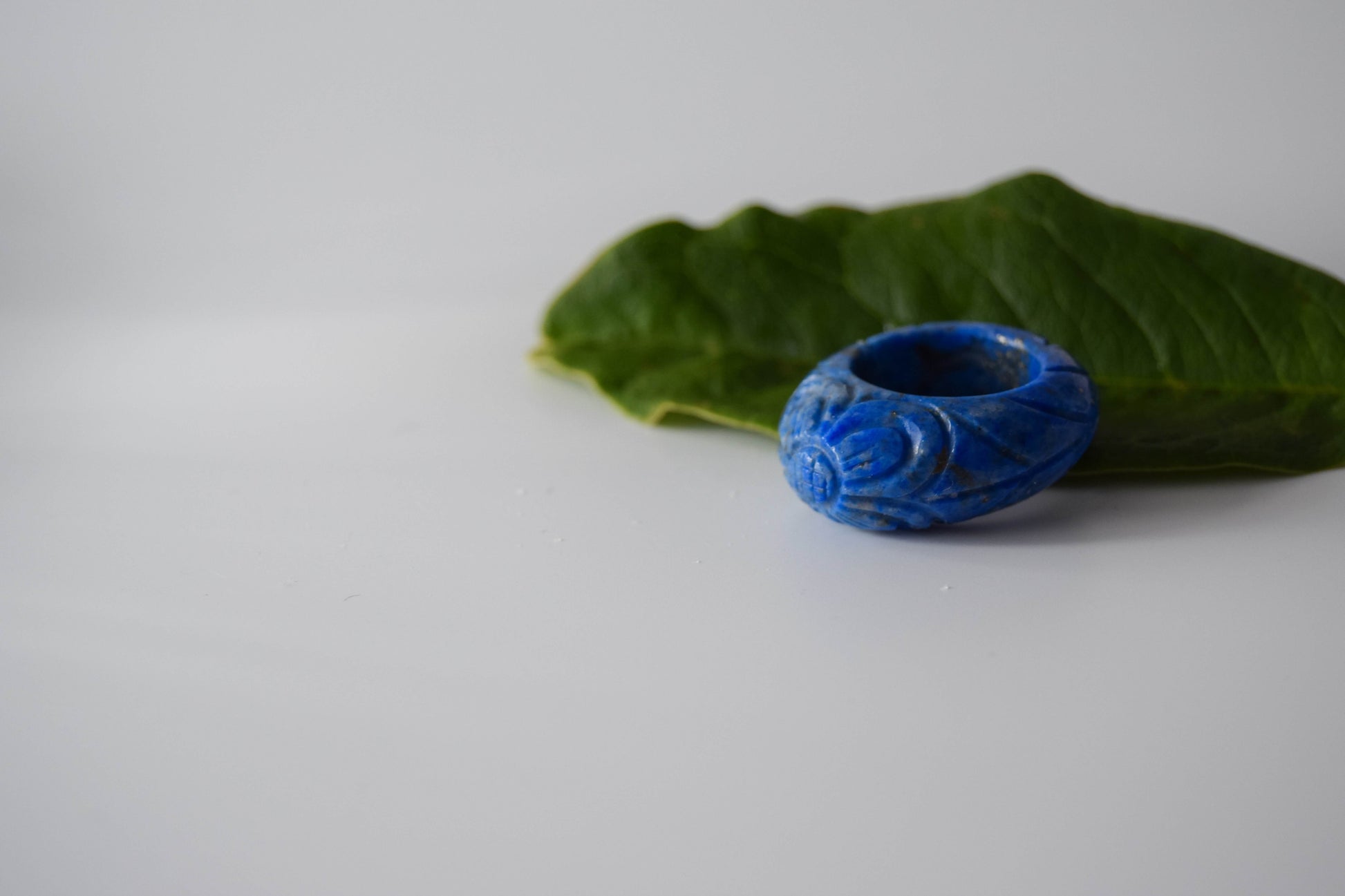 Lapis Lazuli stone ring with carved and engraved flower on a leaf background