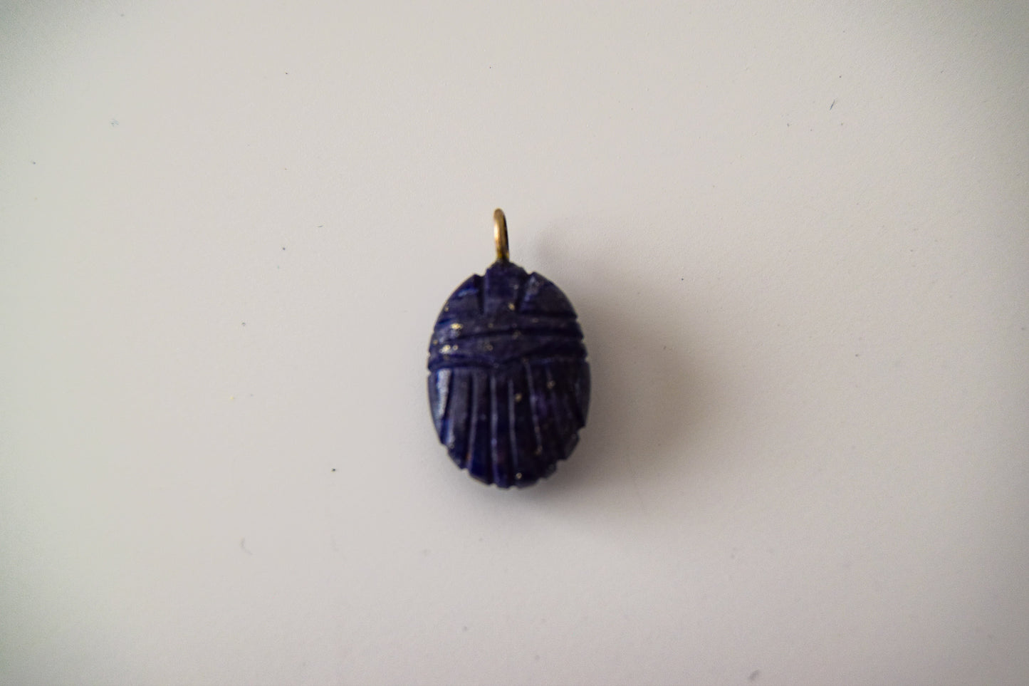 Intricately detailed, this versatile lapis lazuli scarab charm features a delicate scarab design carved from lapis lazuli gemstone, with the pendant ring made of silver plated material, it is  perfect for various jewelry creations like a necklace or earrings, displayed on a neutral background