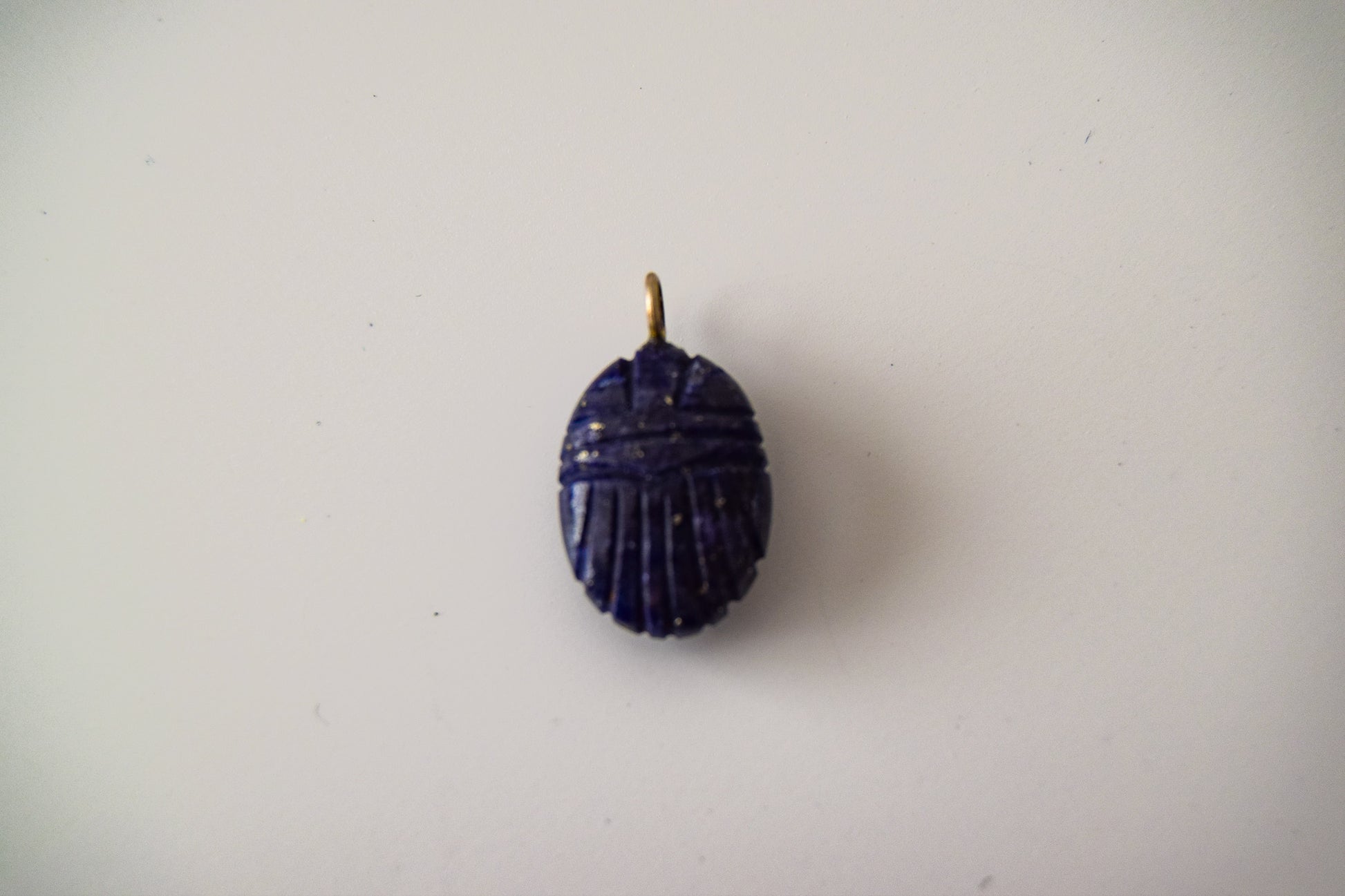 Intricately detailed, this versatile lapis lazuli scarab charm features a delicate scarab design carved from lapis lazuli gemstone, with the pendant ring made of silver plated material, it is  perfect for various jewelry creations like a necklace or earrings, displayed on a neutral background