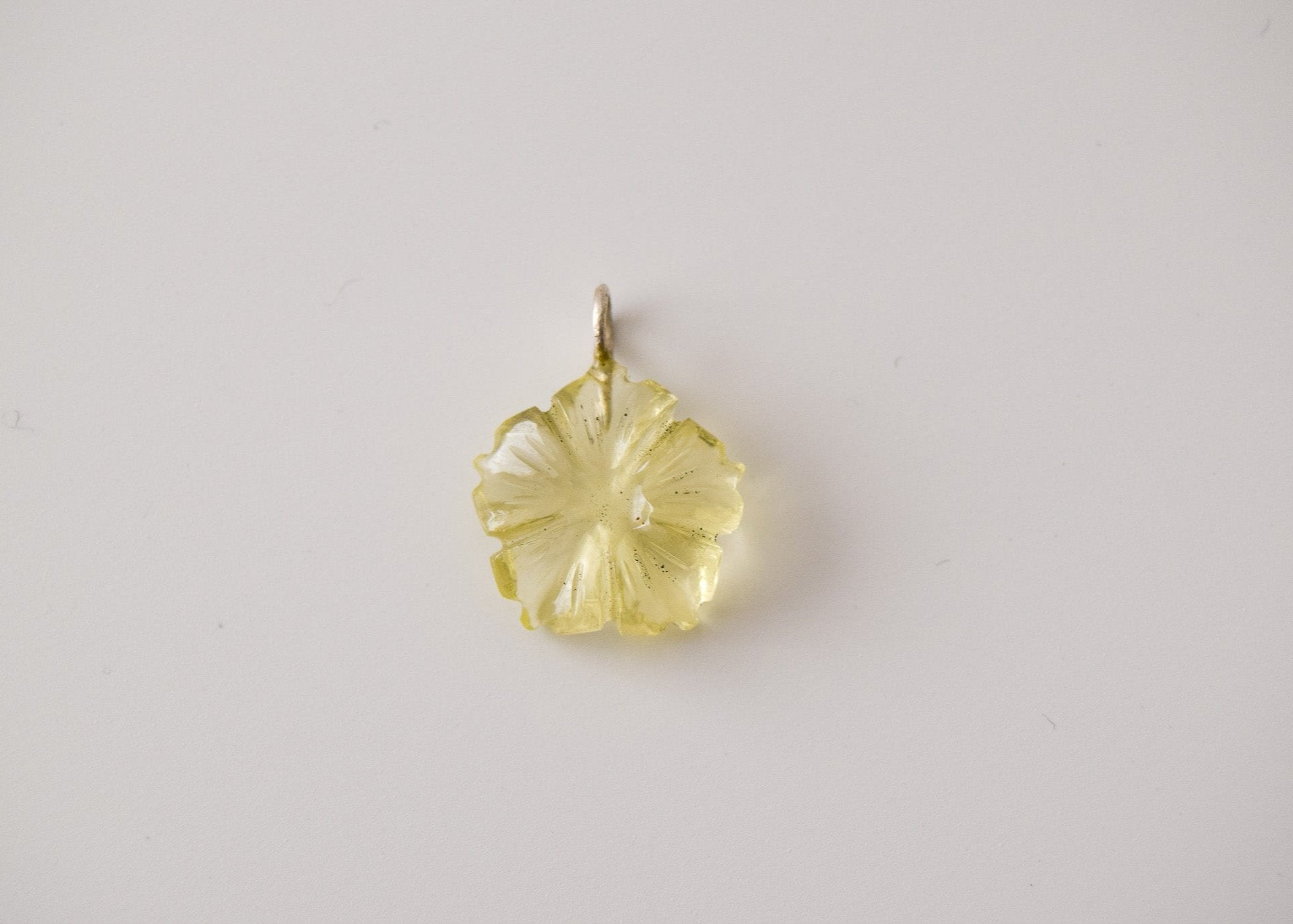 Intricately detailed, this versatile lemon quartz flower charm features a delicate flower design carved from lemon quartz gemstone, it is  perfect for various jewelry creations like a necklace or earrings, displayed on a neutral background