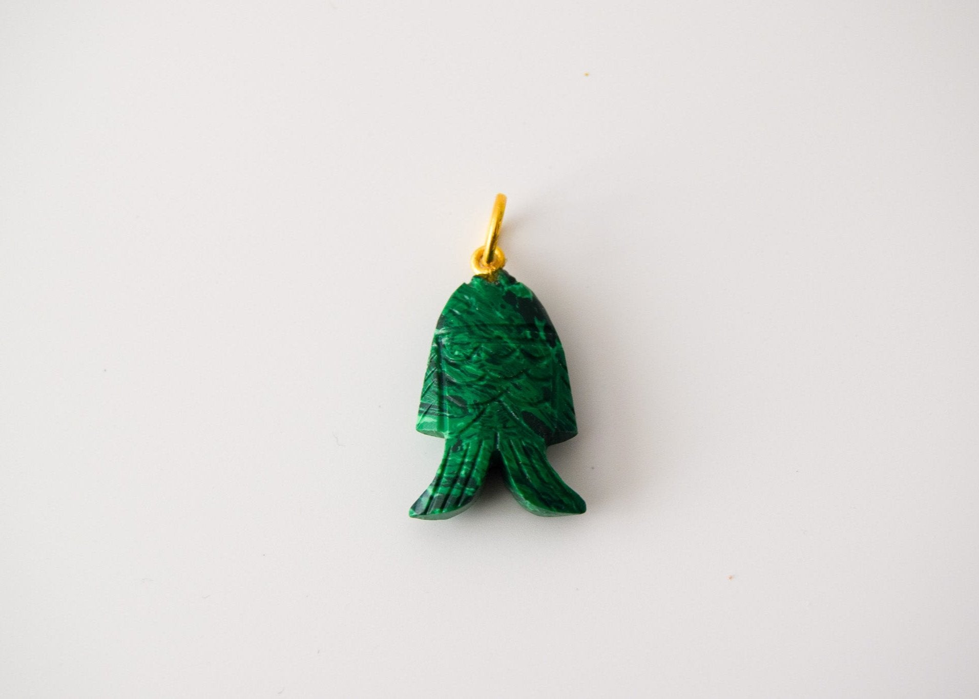 Intricately detailed, this versatile malachite fish charm features a delicate fish design carved from malachite gemstone, with the pendant ring made of gold plated material, it is perfect for various jewelry creations like a necklace or earrings, displayed on a neutral background