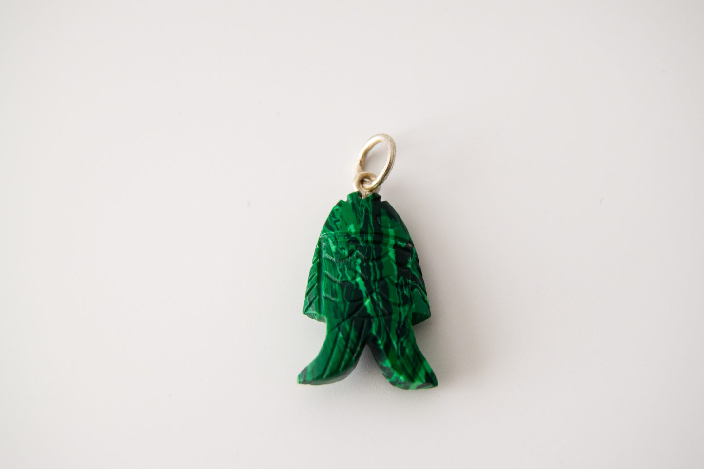 Intricately detailed, this versatile malachite fish charm features a delicate fish design carved from malachite gemstone, with the pendant ring made of silver plated material, it is perfect for various jewelry creations like a necklace or earrings, displayed on a neutral background