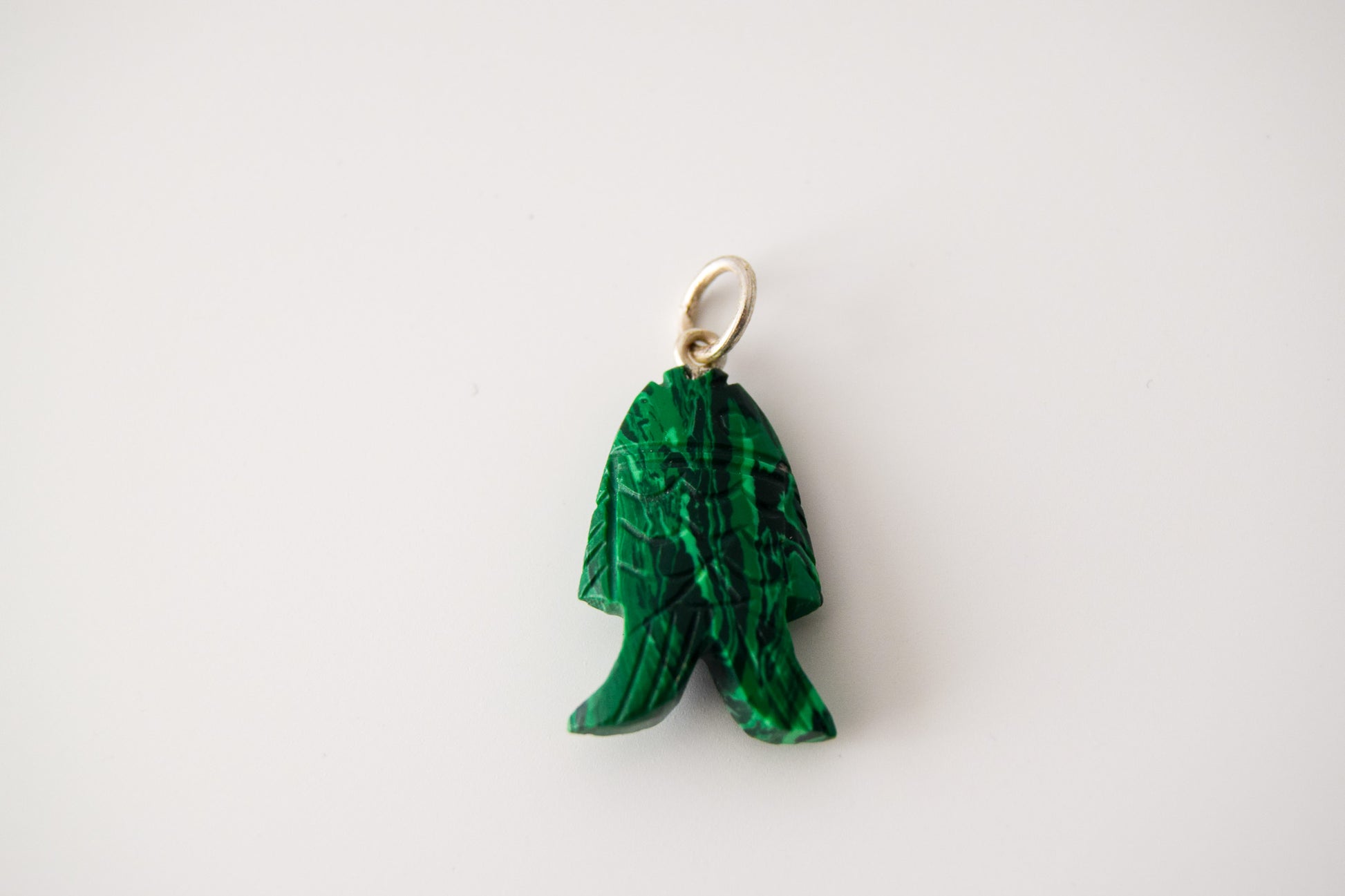 Intricately detailed, this versatile malachite fish charm features a delicate fish design carved from malachite gemstone, with the pendant ring made of silver plated material, it is perfect for various jewelry creations like a necklace or earrings, displayed on a neutral background