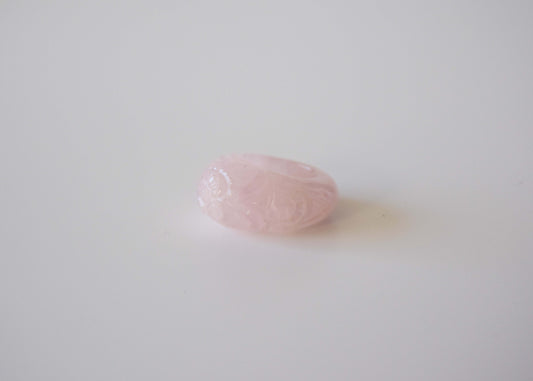 Rose Quartz stone ring with carved and engraved flower on a neutral background