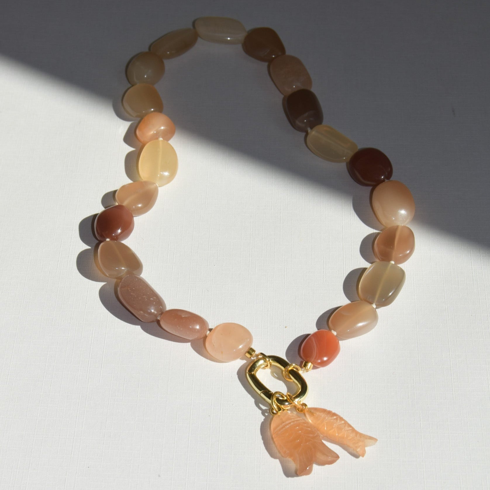 Beaded bracelet with a fish charm on a white background
